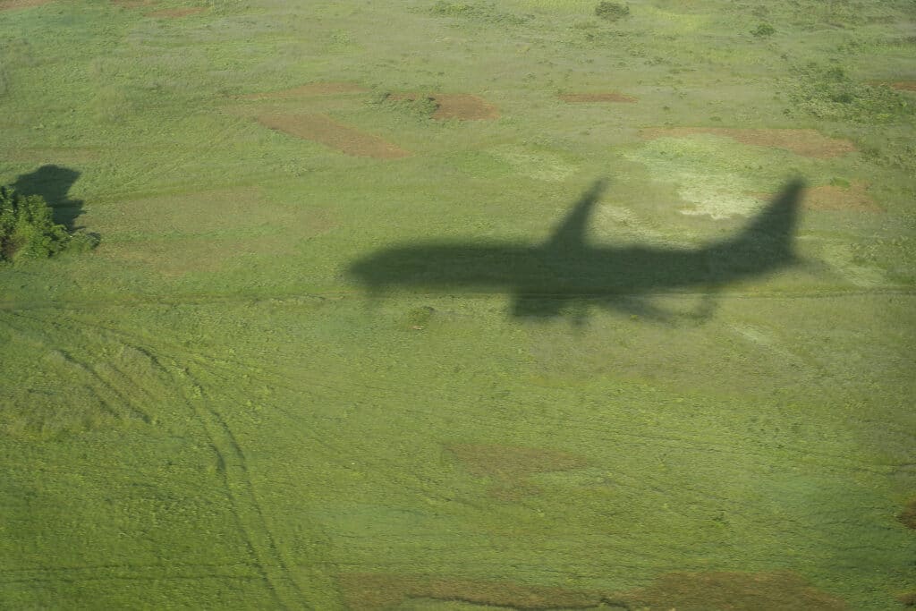 Shadow of the plane in the green fields during the landing